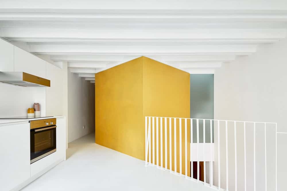 This is a look at the edge of the kitchen showcasing the cooking area that is behind the large yellow structure housing the staircase.