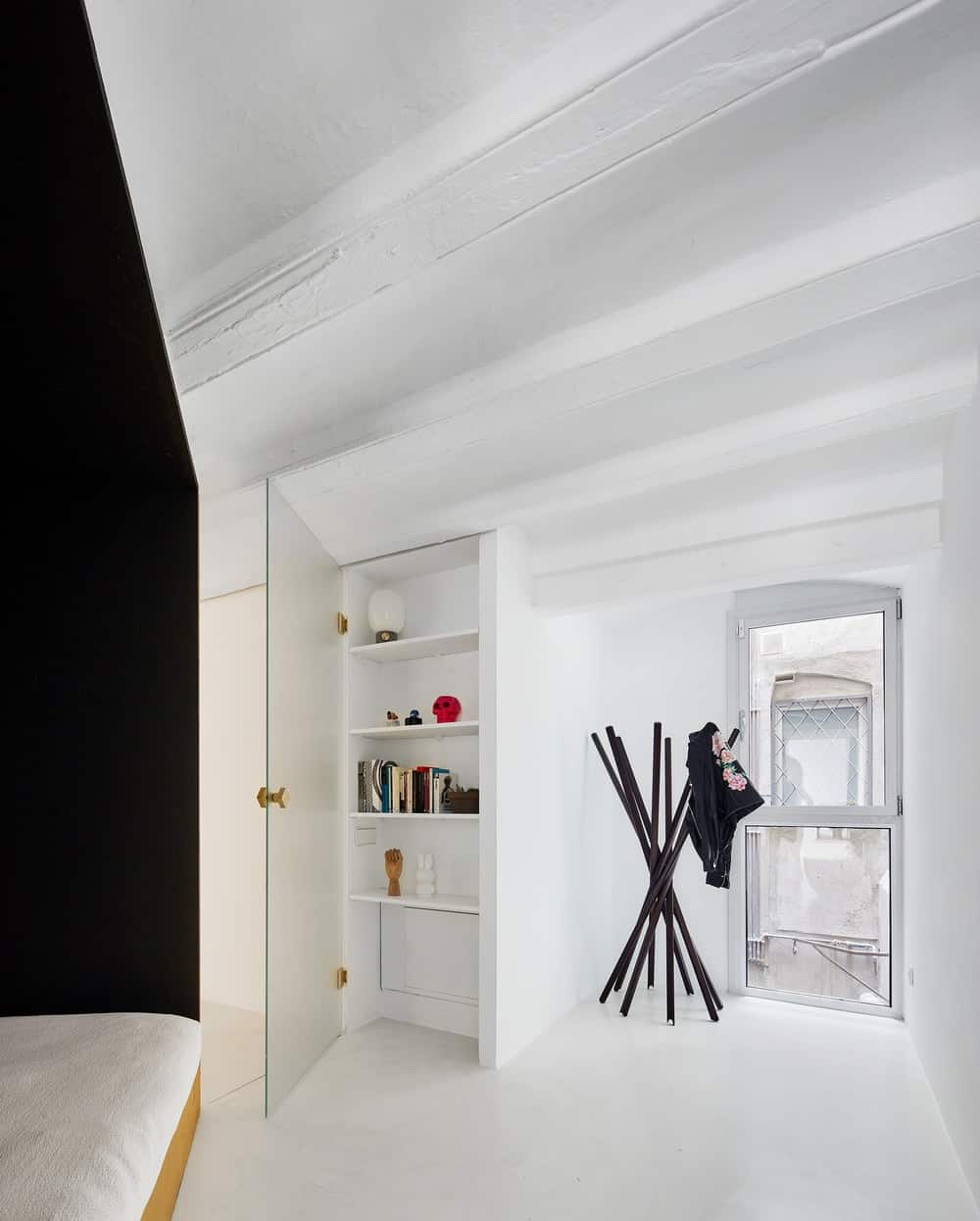 This is the other side of the bed structure with a white cabinet that blends perfectly with the white floor, walls and beamed ceiling.