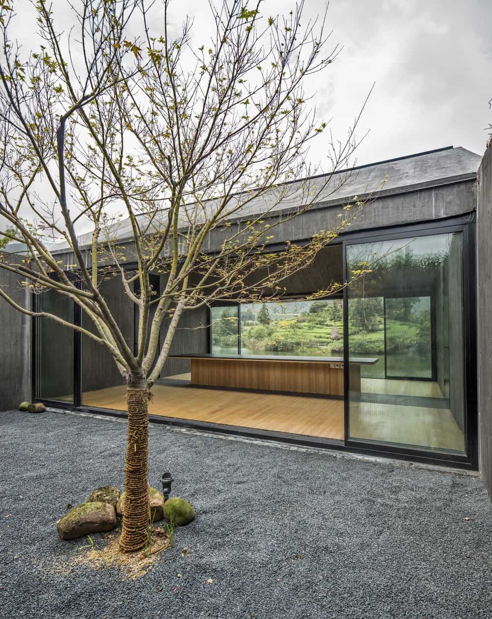 This is an area of the teahouse with a zen garden, a large room with glass walls and sliding glass doors and a large counter in the middle.