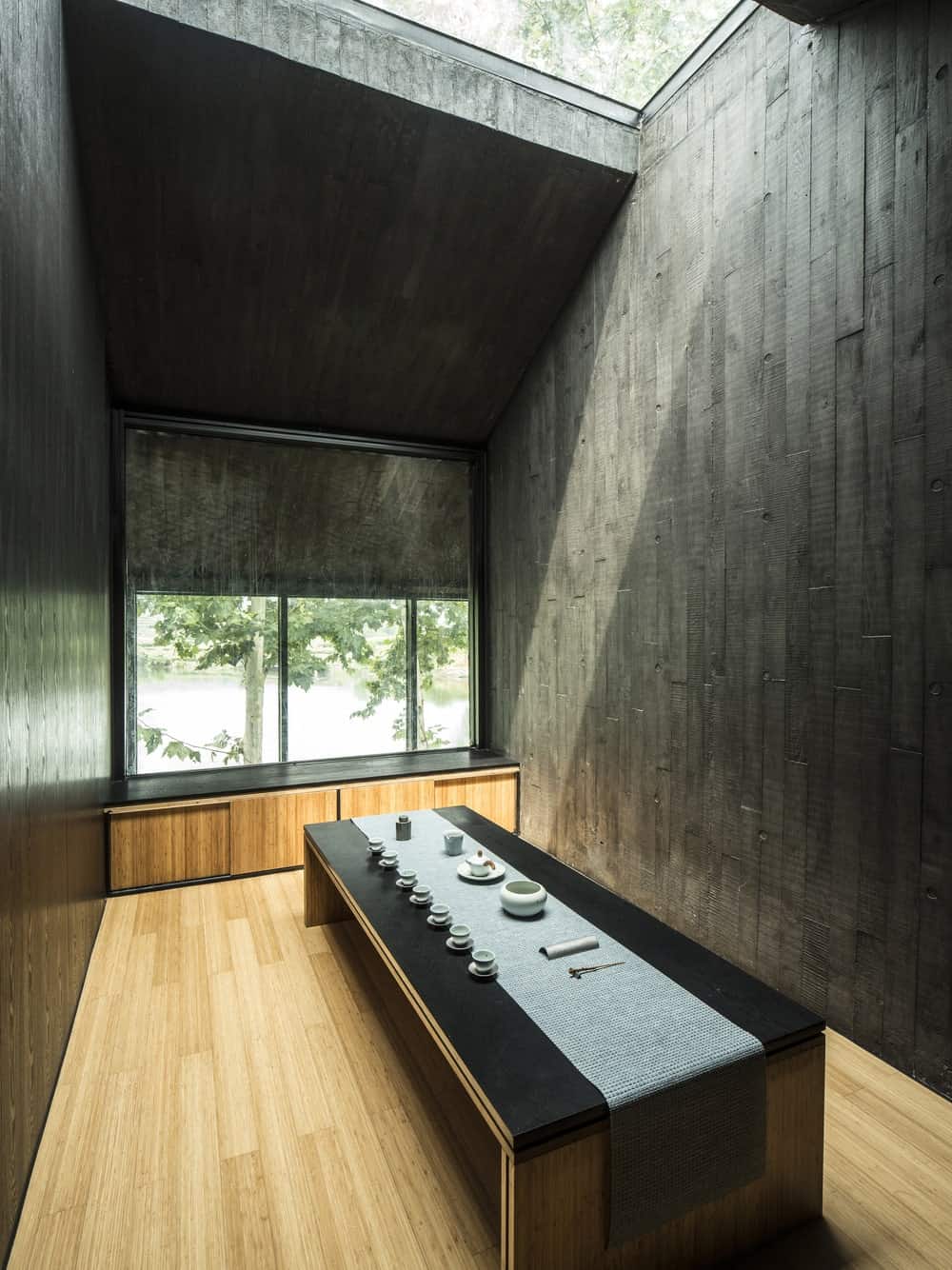 This is a small room with atall ceiling that has a skylight. These are paired with a low table and a contrasting light hardwood flooring.