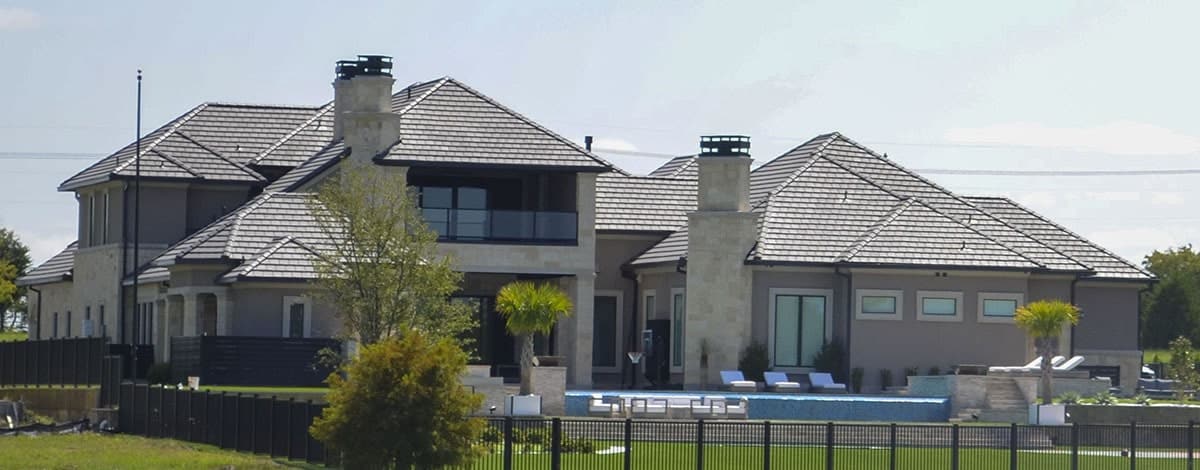 Rear exterior view with outdoor lounge, pool, cabana, and an upper balcony enclosed in glass railings.