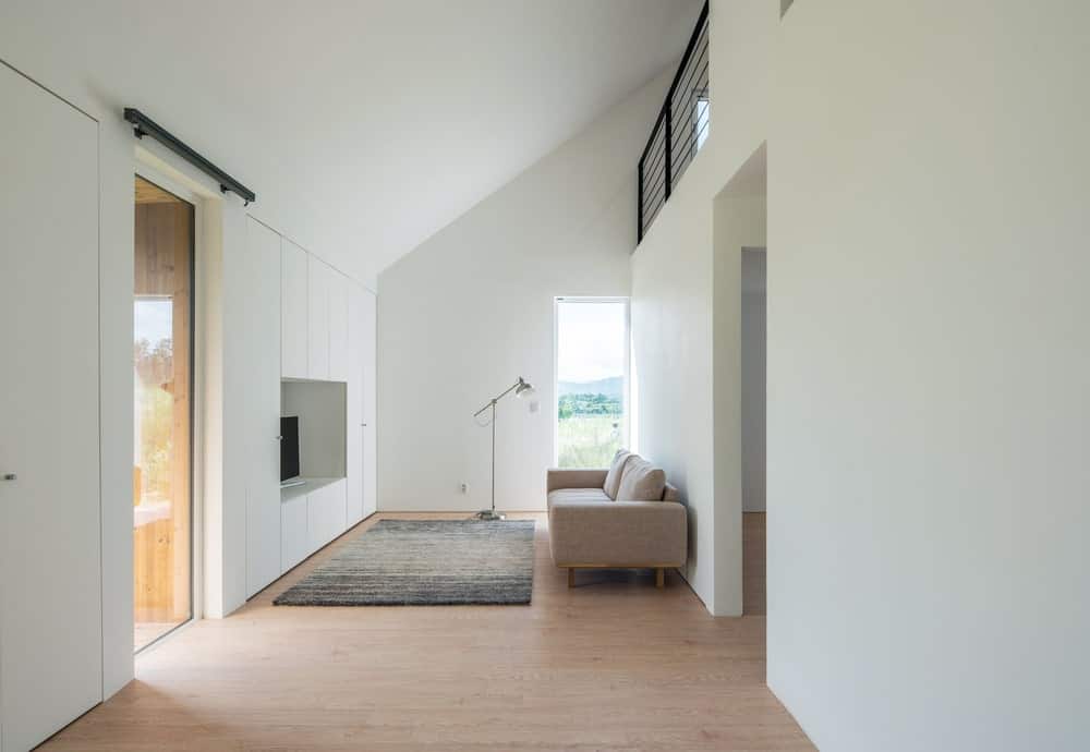 This is the living room with white walls, a brown sofa paired with an area rug.
