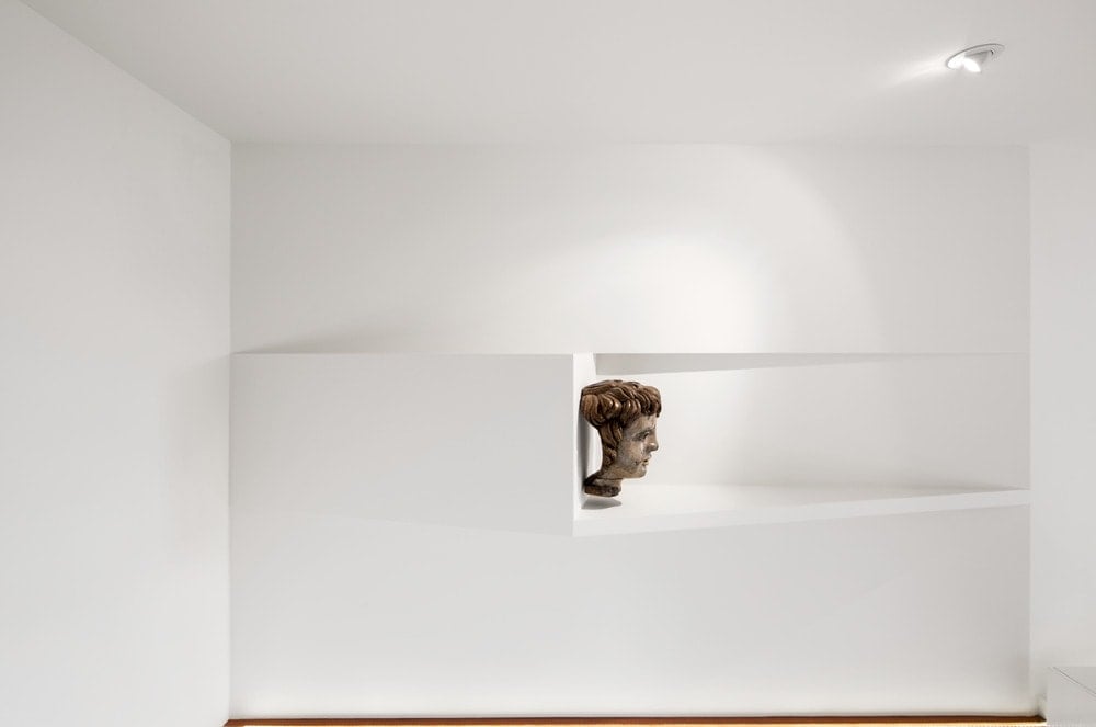 The white concrete beams above the stairs is adorned with a head sculpture display.