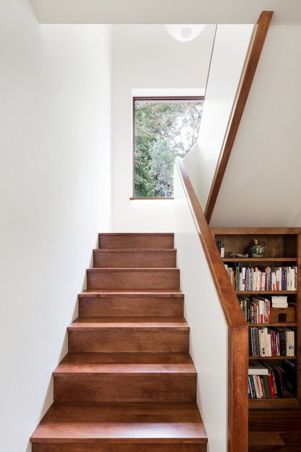 This is a close look at the staircase with wooden steps to pair with the wooden built-in shelves on the side.