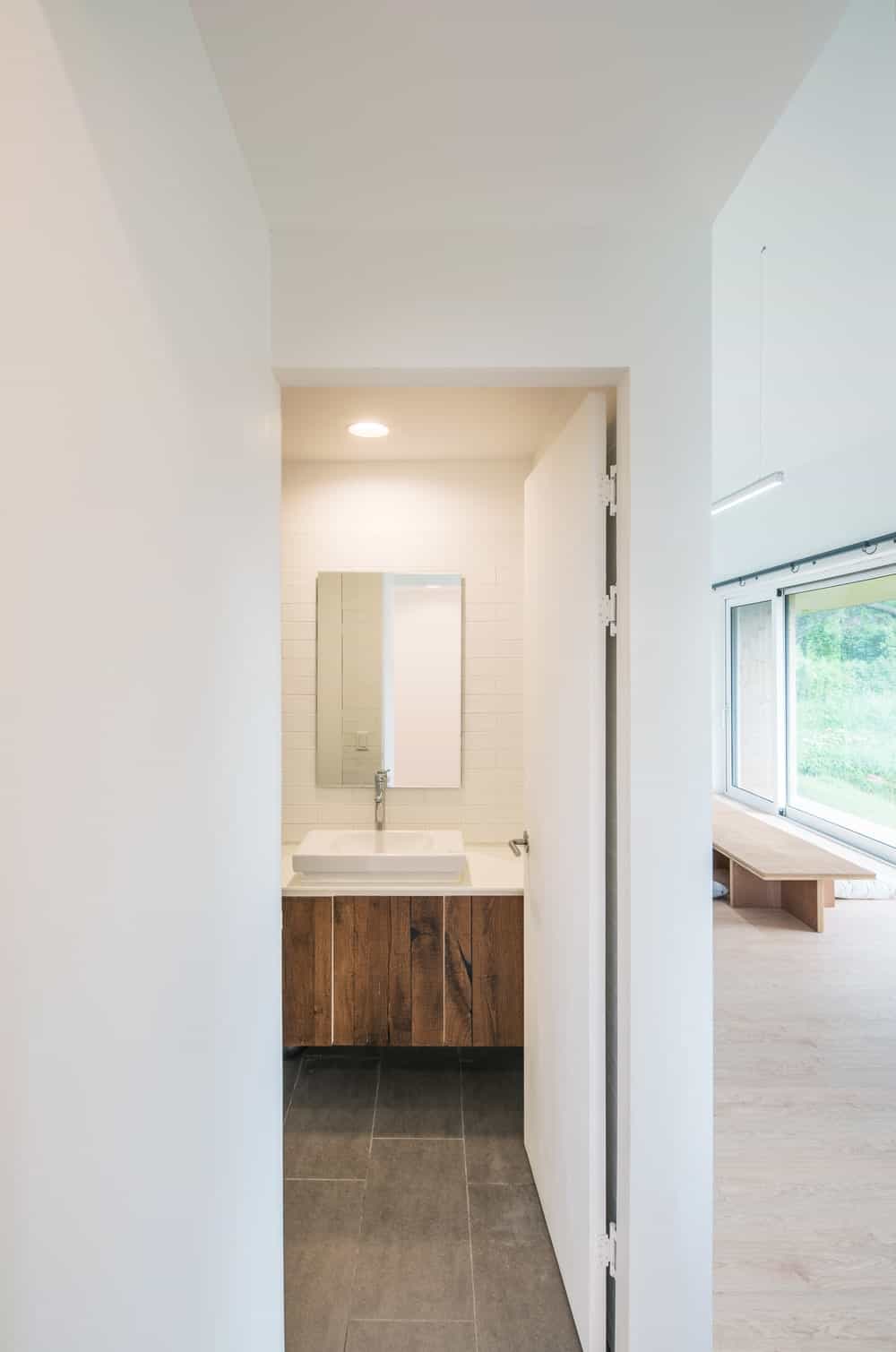 The bathroom has a brown wooden floating vanity with a wall-mounted mirror above.