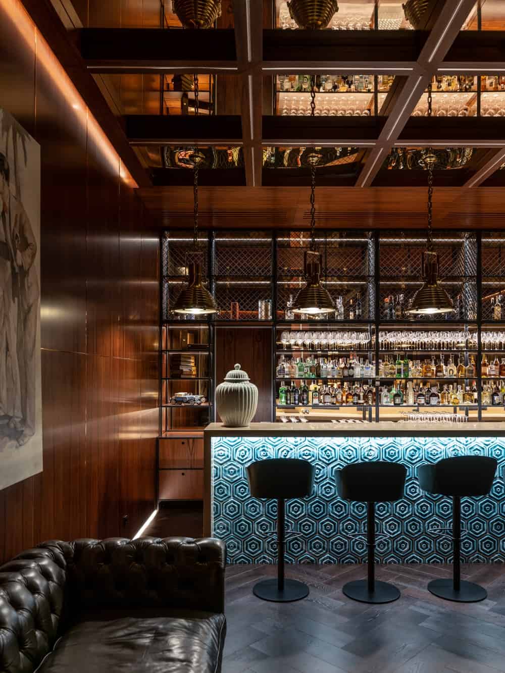 This is the bar of the house with a collection of alcoholic beverages at the shelves across from the bar.
