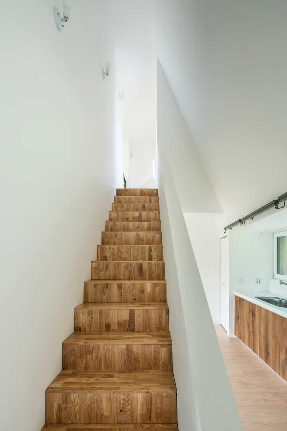This is a close look at the wooden steps of the stairscase that makes it stand out against the bright walls on both sides.