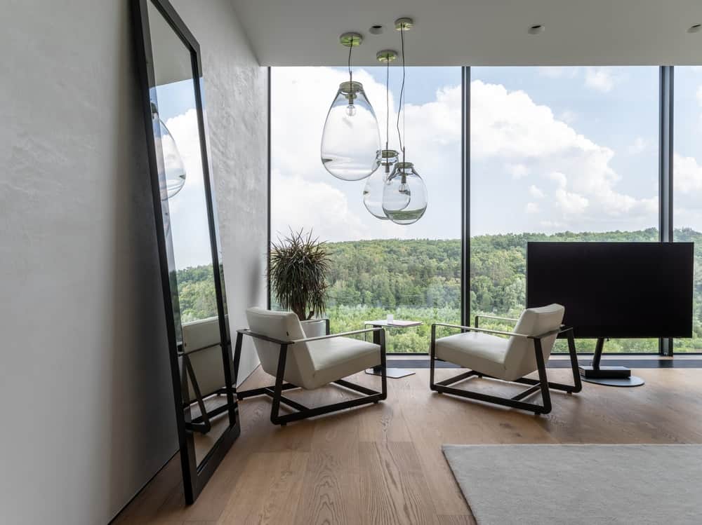 This is a close look at the sitting area of the bedroom with a set of glass pendant lights over the cushioned armchairs.