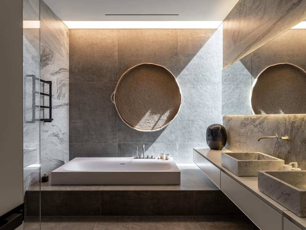 This bathroom has a built-in white bathtub on the far side on a platform by the floating 2-sink vanity.