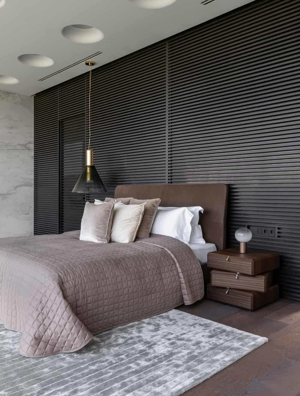The bedroom has a dark brown bed that pairs well with the dark wooden bedside tables and the hardwood flooring.