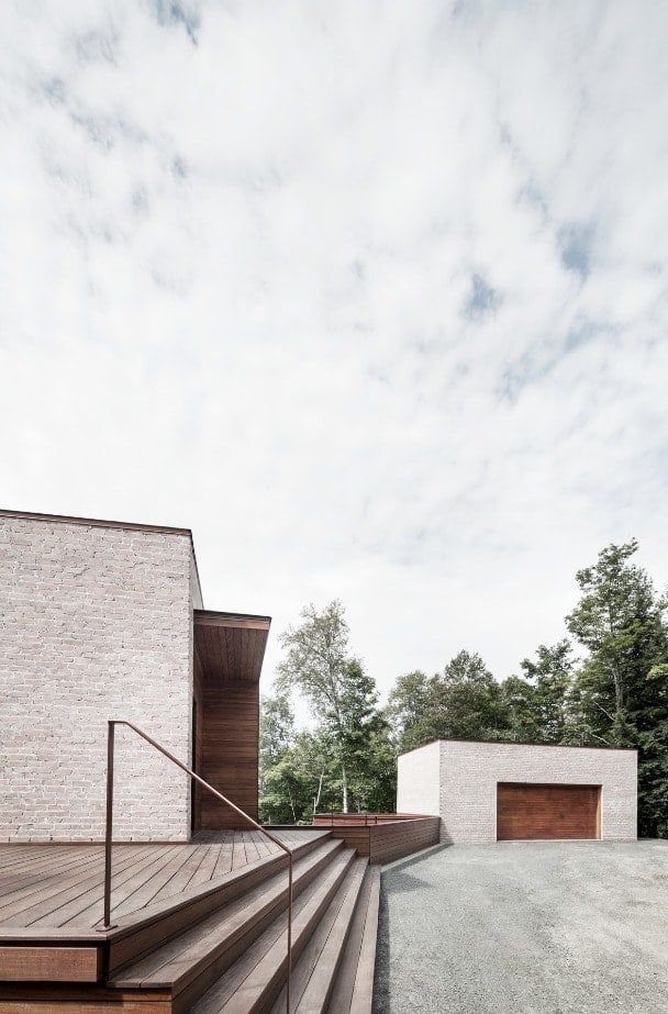 This is a close look at the large wooden elevated deck of the house with a set of steps and railings to lead to the main entrance.