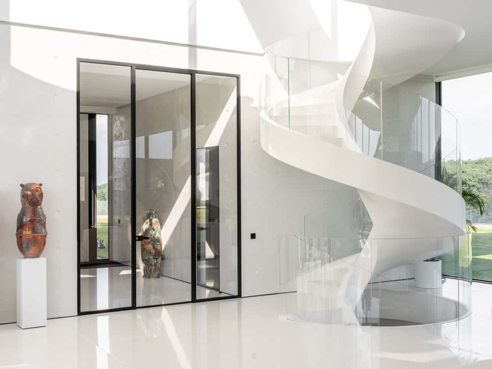 This is the area behind the living room's sofa. It has a white spiral staircase, a glass door and a couple of sculptures.