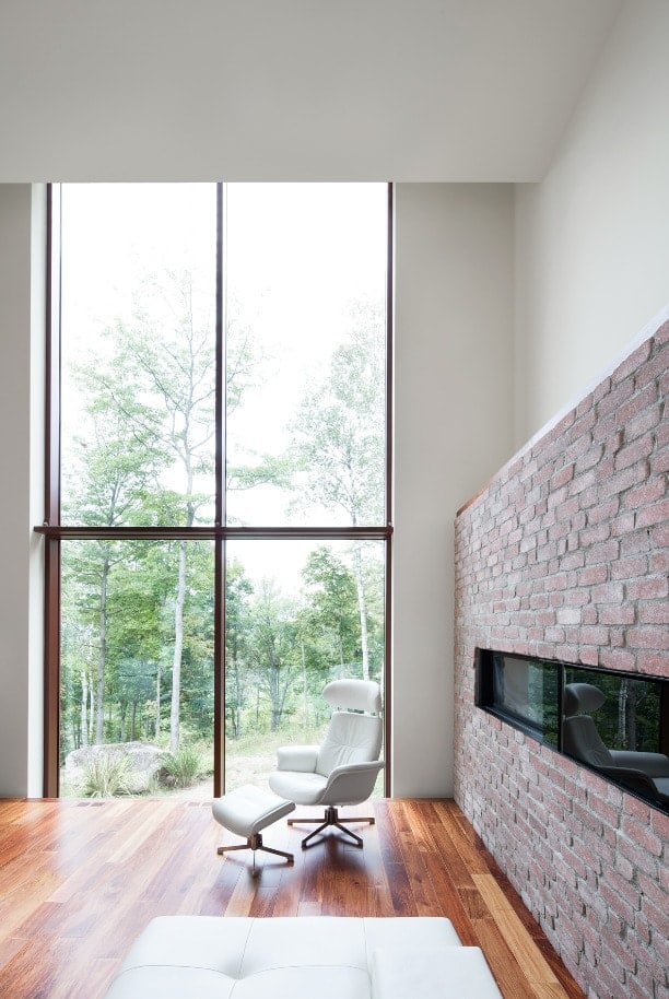 This is a close look at the interior of the house that has a modern fireplace by the large glass wall.