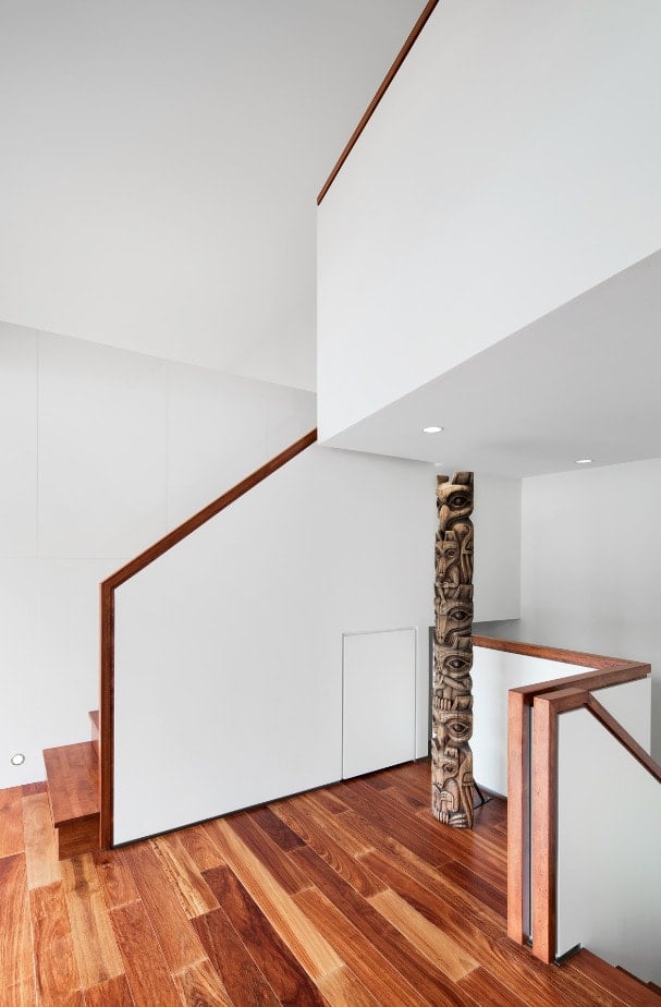 This is a close look at the landing adorned with a large wooden tiki pole that pairs well with the hardwood flooring and wooden banisters.