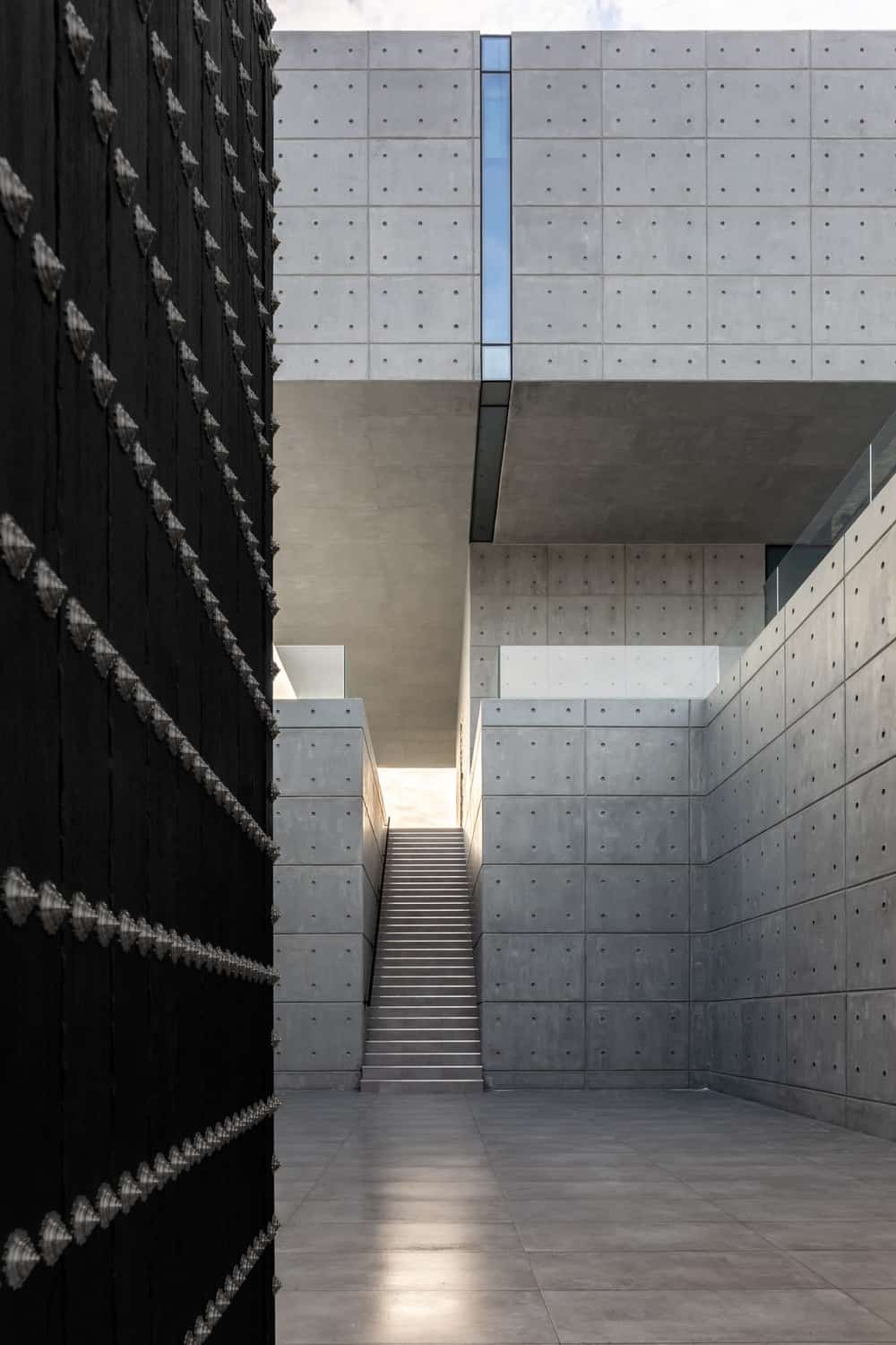 This is a close look at the side of the house with a large concrete courtyard with tall walls and tall concrete ceiling.