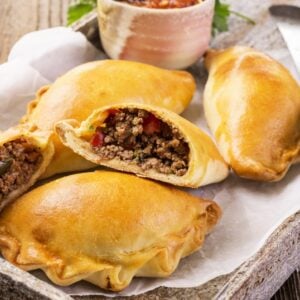 Pieces of beef empanadas on a rustic spread on top of a wooden table.