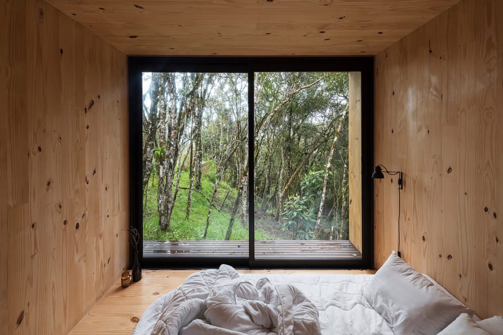 On the far side from the bed is the glas wall that brings in natural lighting.