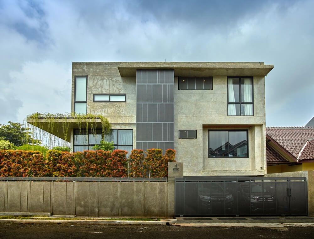 This is a front view of the house with its unique design and various window along with a large front gate.