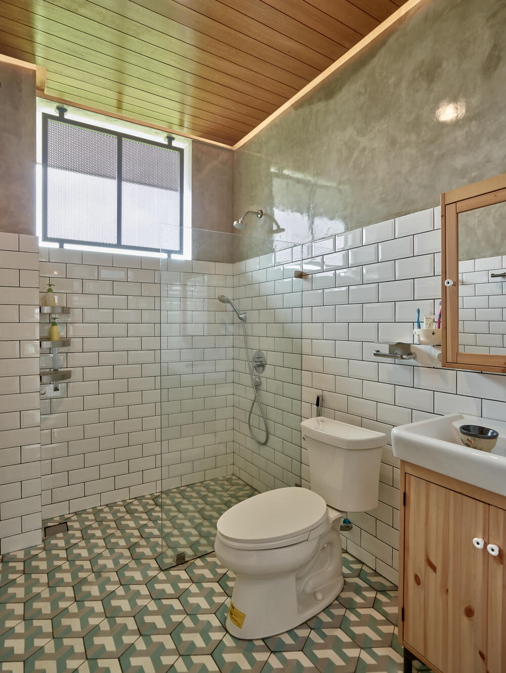 The bathroom has white subway tiles on its walls paired with patterned tiles on the floor that make the toilet and vanity stand out.