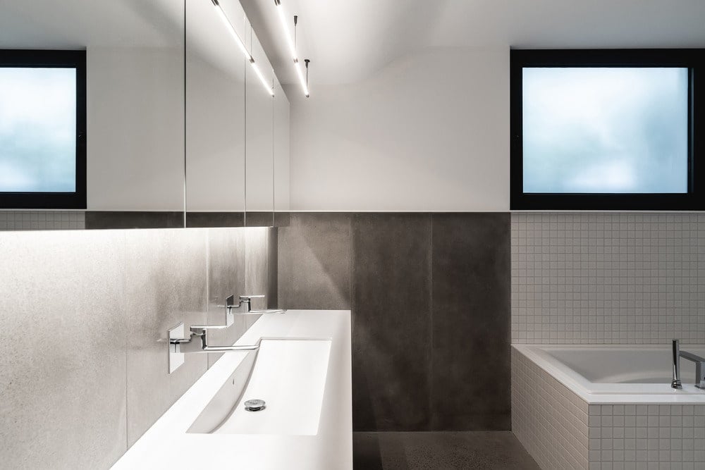 This other bathroom has dark tiles on its lower half of the walls contrasted by the white sink, walls and bathtub.