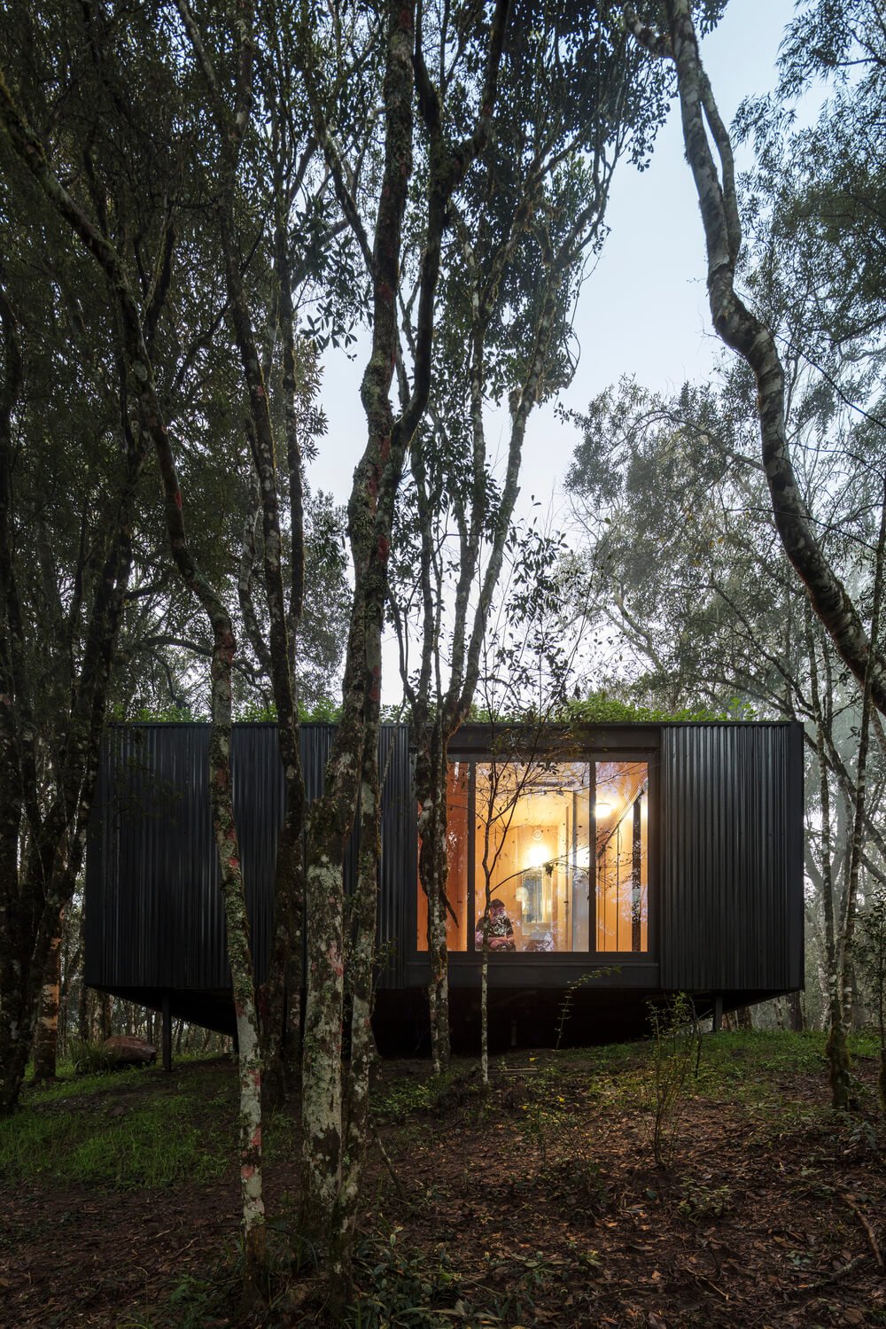 This side of the house has dark textured exterior walls complemented by the large glass window.