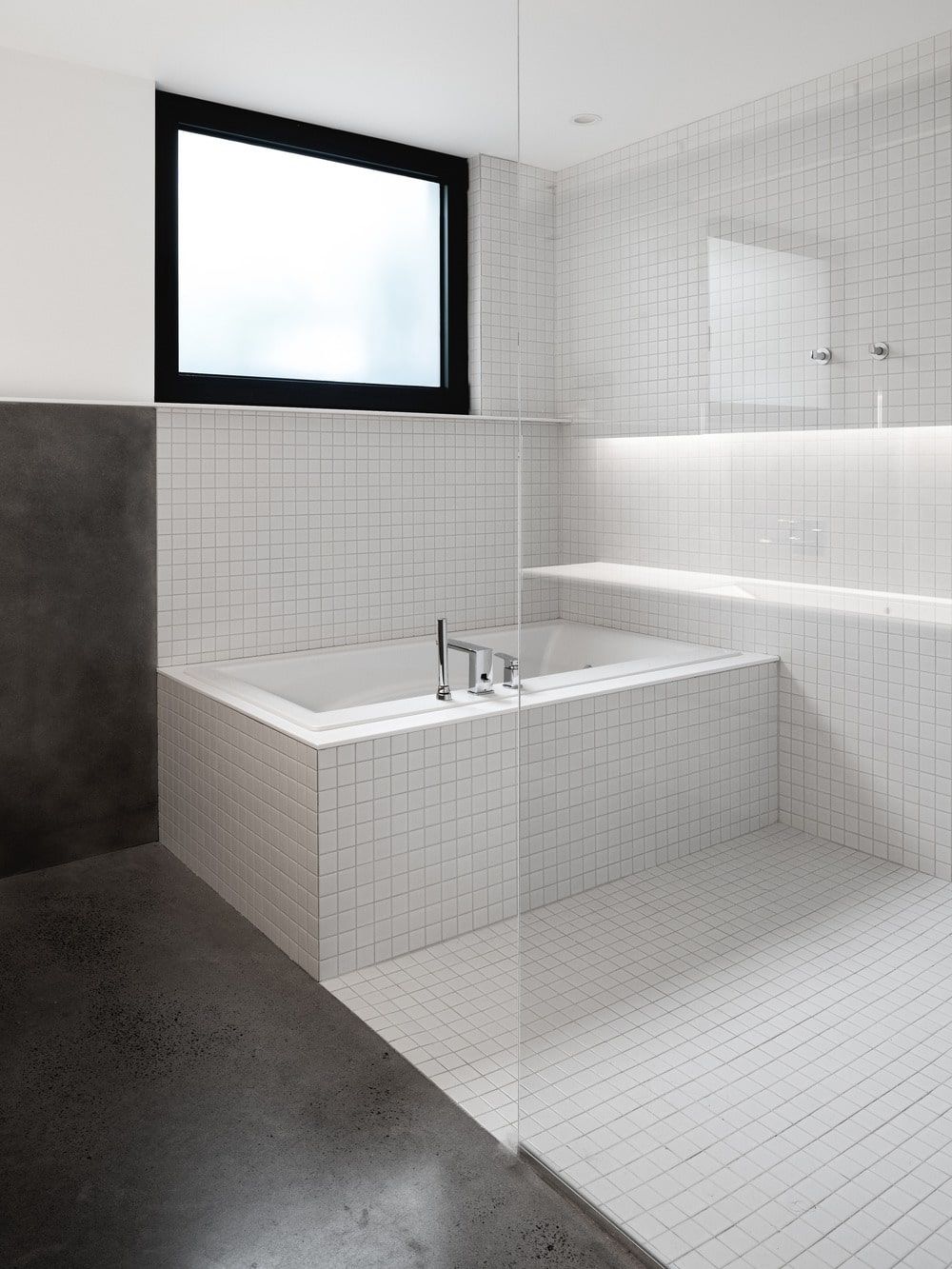 The bathtub is inside a glass-enclosed wet area.