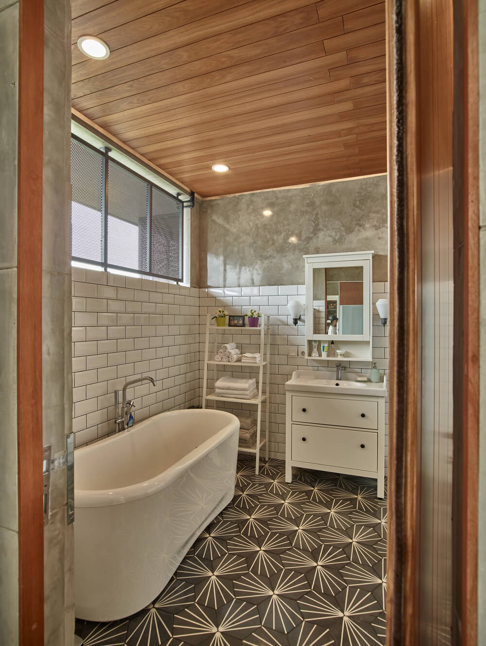 This other bathroom has a large freestanding bathtub under the window paired with white subway tiles on the walls.