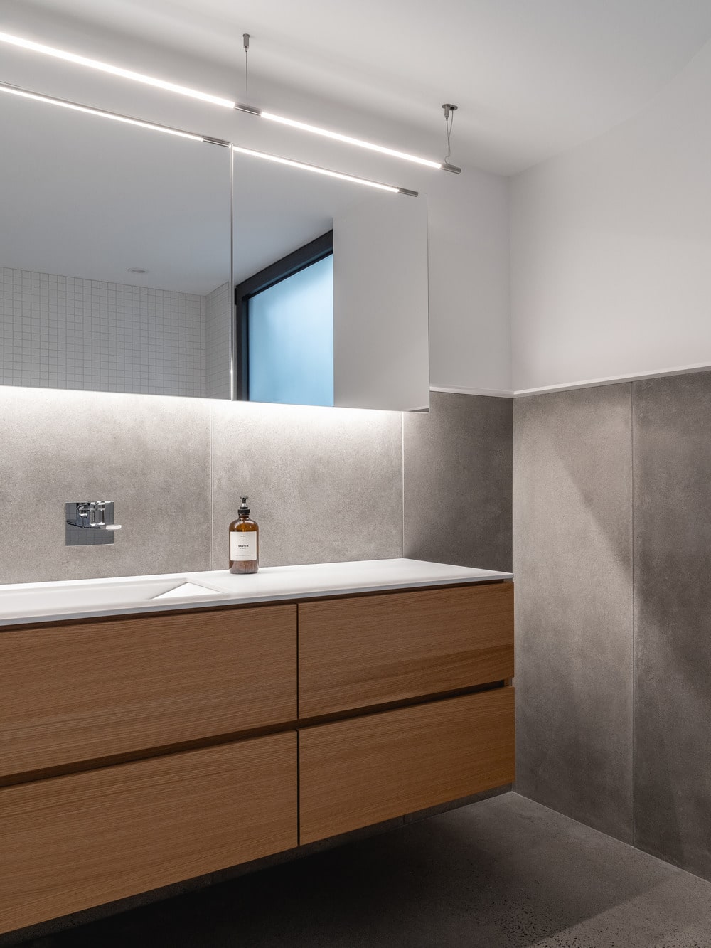 The vanity of the bathroom has bright walls and modern lighting.