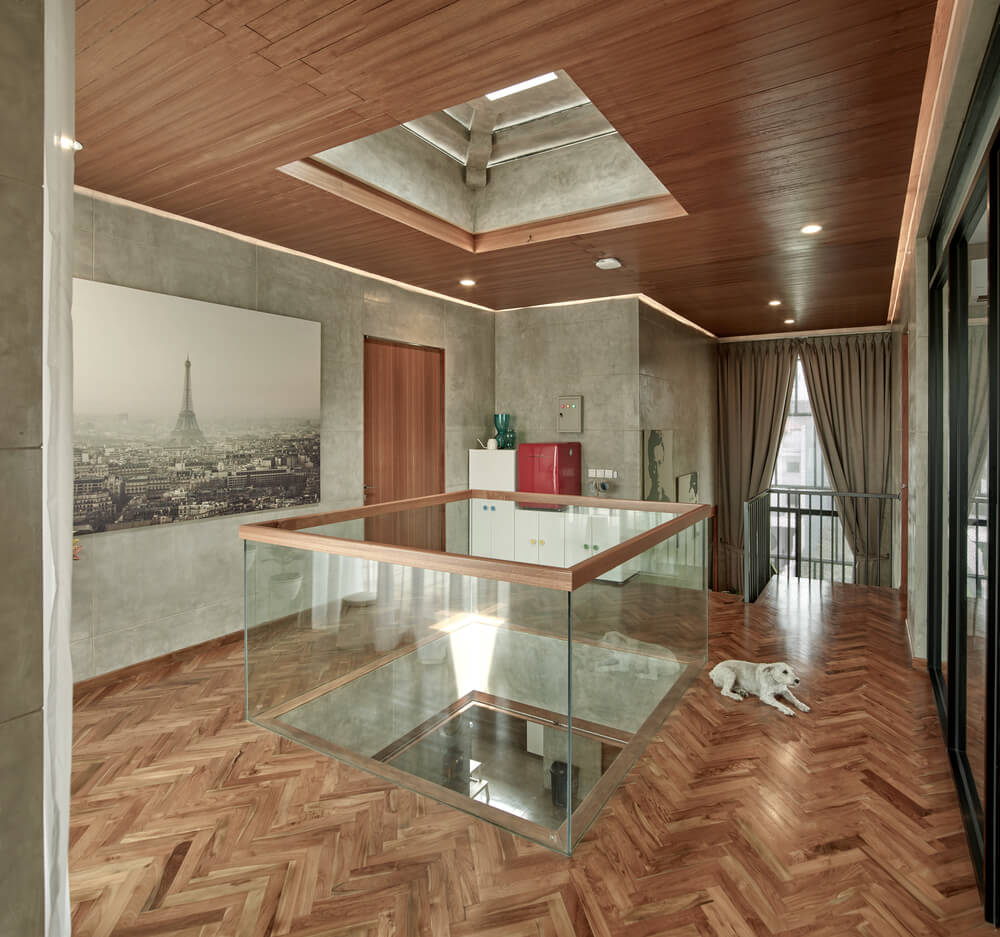 The glass walls of the indoor balcony is surrounded by herringbone hardwood flooring.