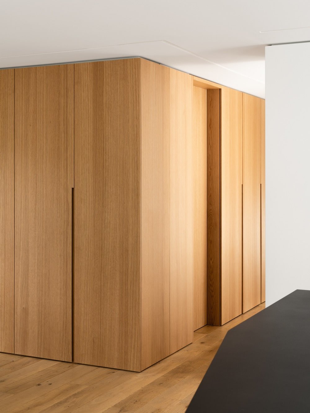 The bathroom has wooden walls and door that matches the tone of the floor.