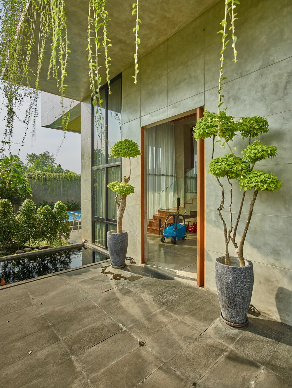 This is the main entrance of the house with a couple of potted plants flanking the main door and small fish pond on the side.