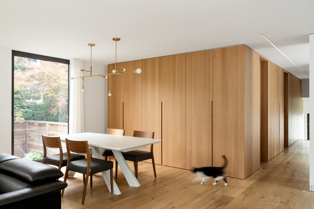 Next to the dining table is the large wooden paneled wall that matches the floor.