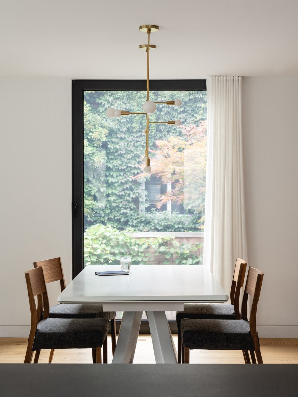 This is a close look at the dining area with a large white rectangular table topped with a simple chandelier that matches the foyer's.