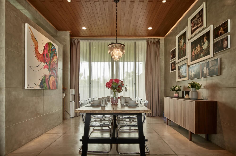 On the other side of the table is a waist-high dining room cabinet topped with a collection of framed artworks.