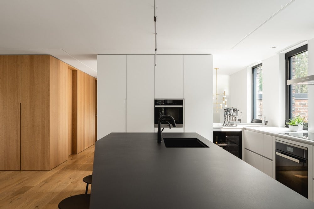 This is a close look at the kitchen island with a black countertop that stands out against the bright walls and ceiling.