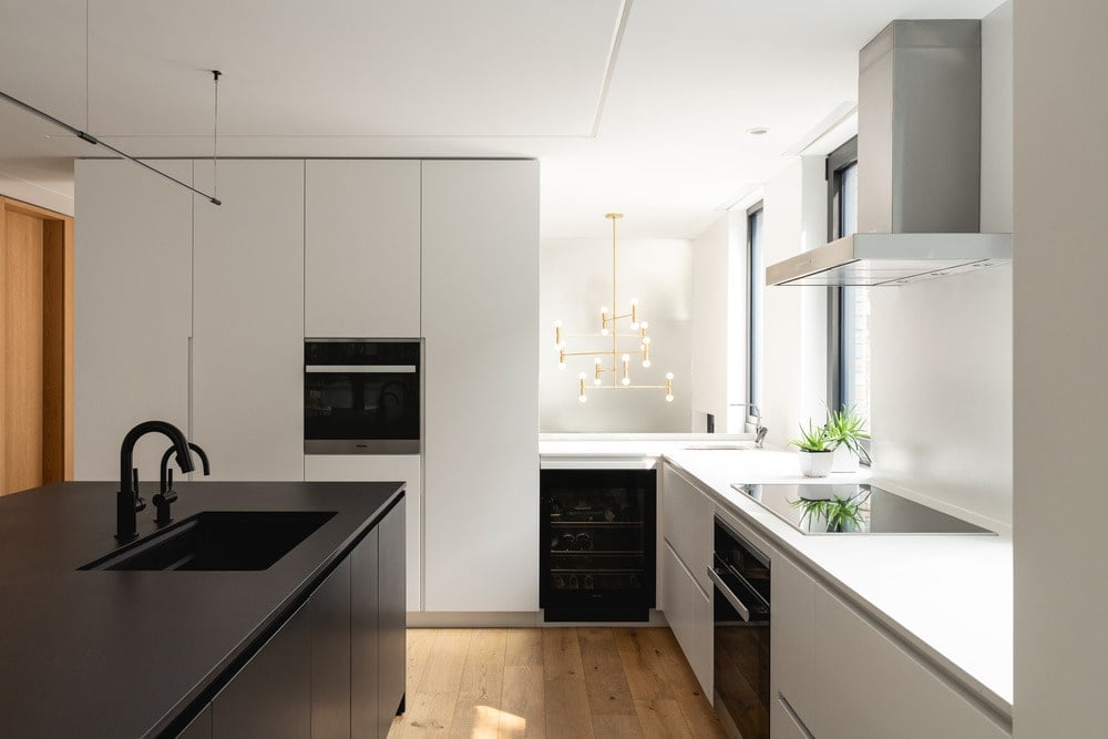 The black appliances stand out against the white cabinetry lining the walls.