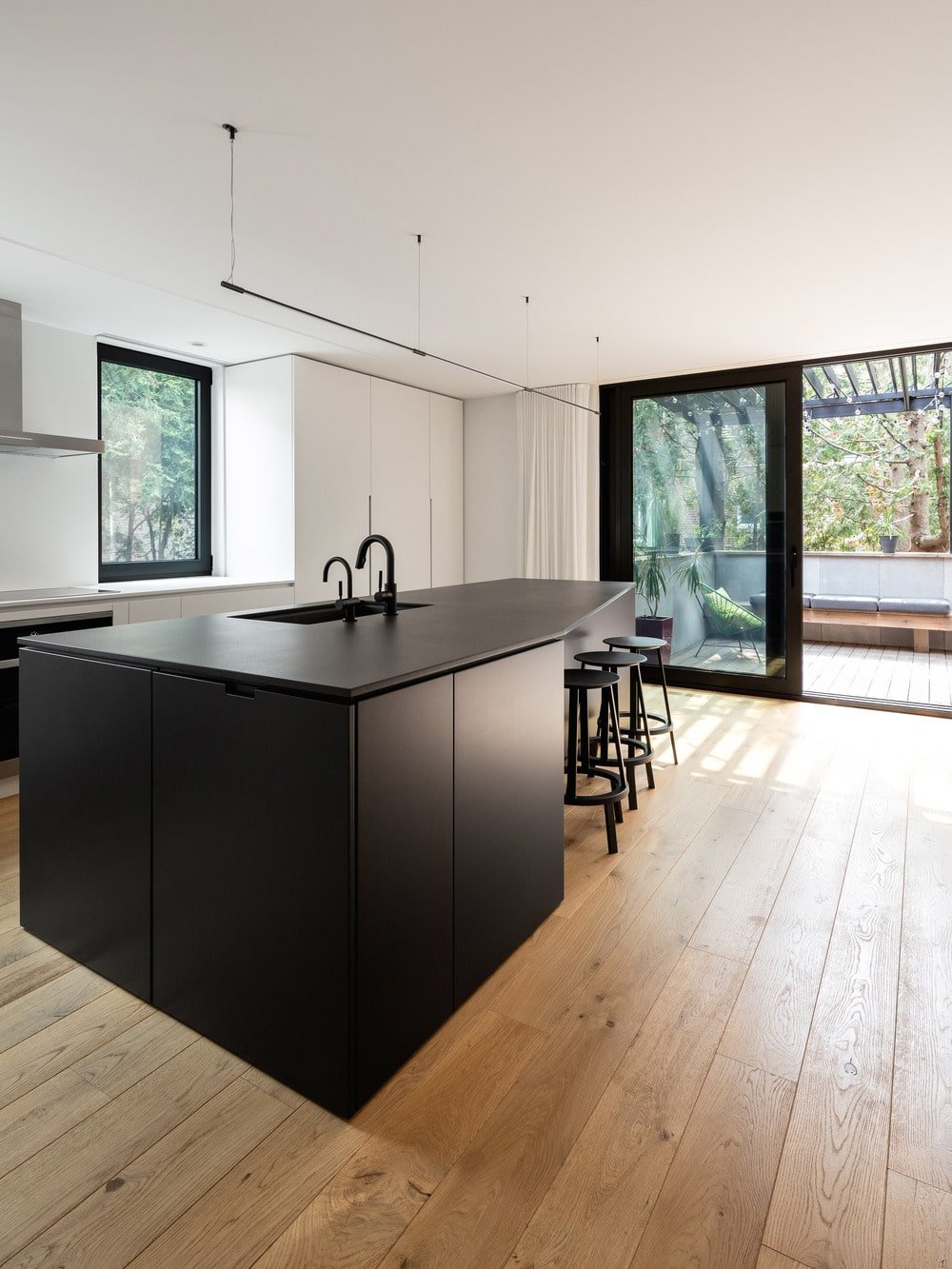 The kitchen has a large black kitchen island that stands out against the hardwood flooring.