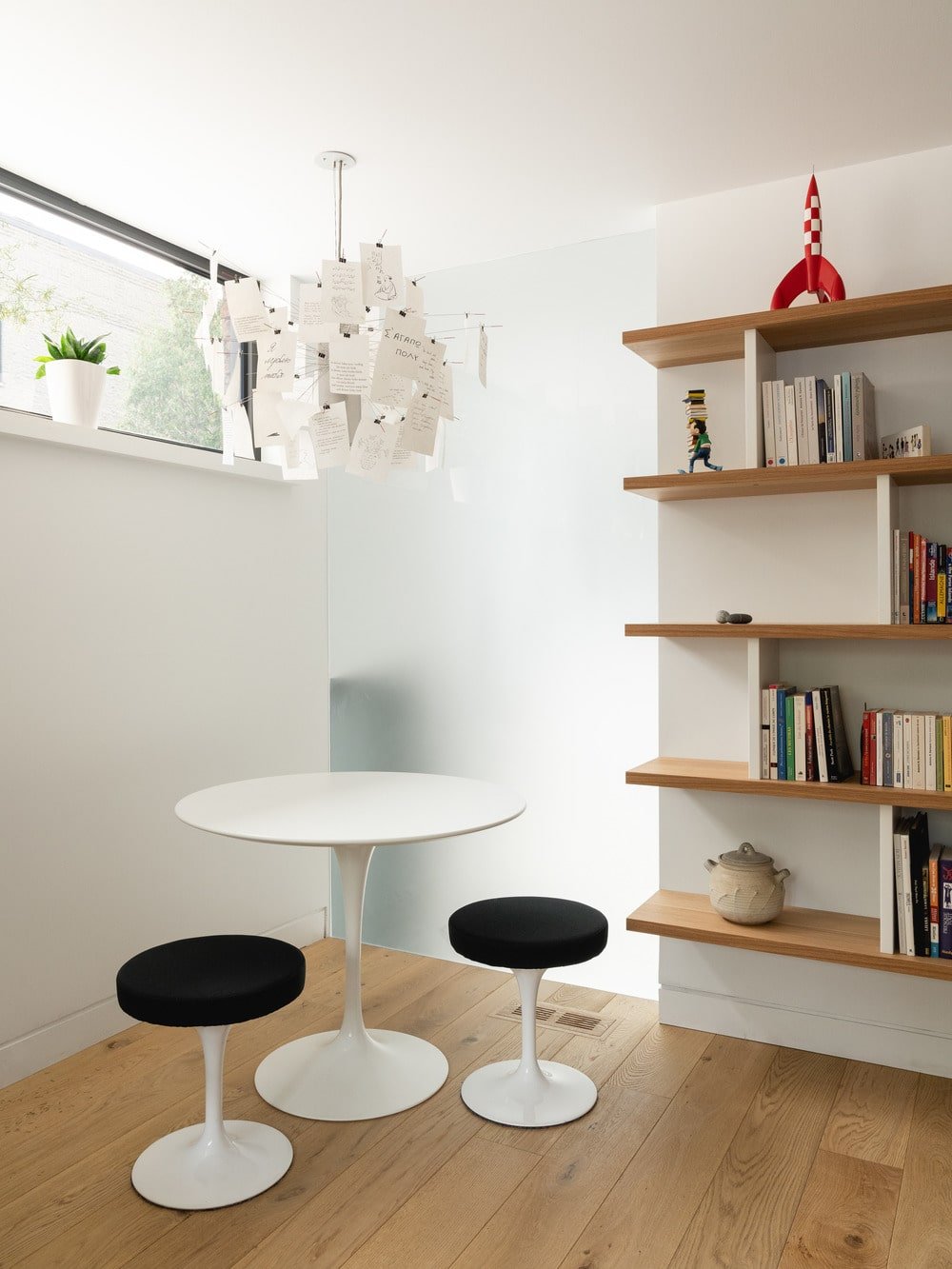 This is a corner library with a round white modern table next to a built-in modern shelf.