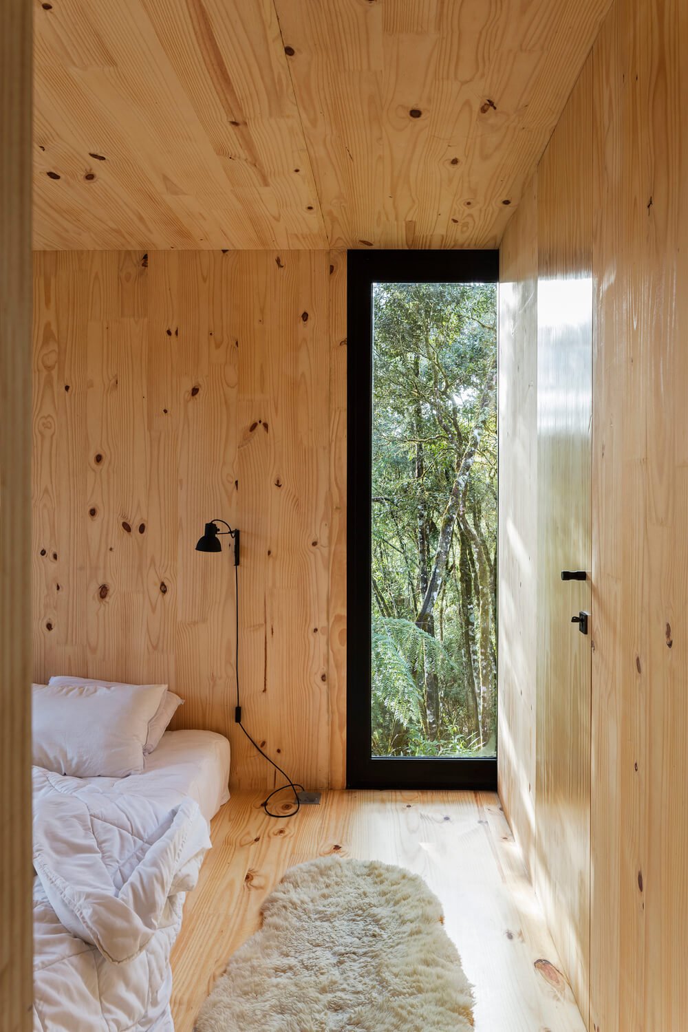 This simple bedroom has a large platform bed topped with mounted lamps.