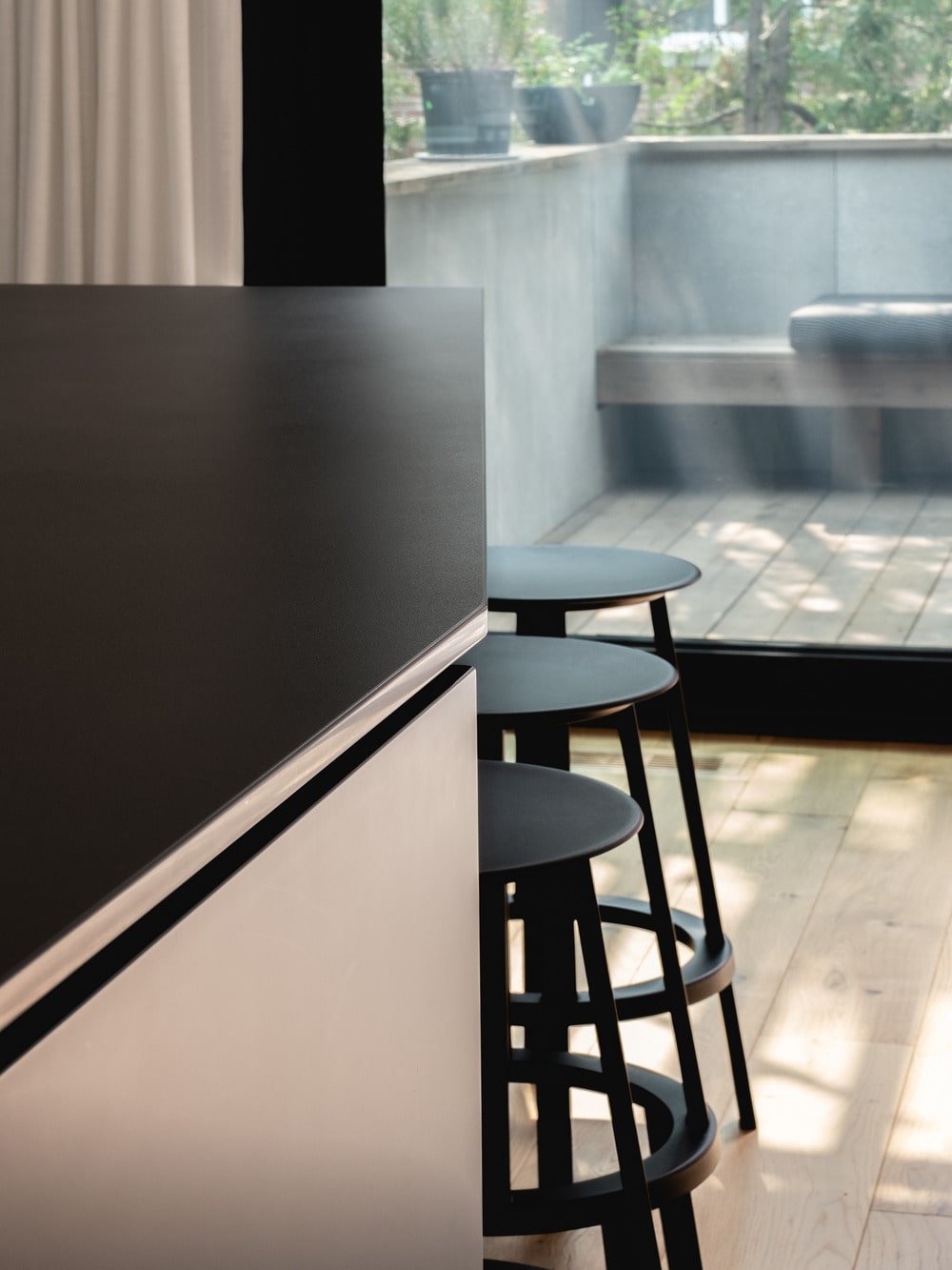 This is a close look at the kitchen island and its three black kitchen stools.