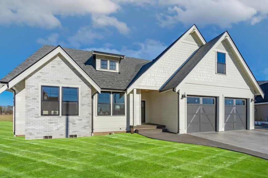 Front exterior view with brick and shake accents, double garage, and entry porch lined with a single post.