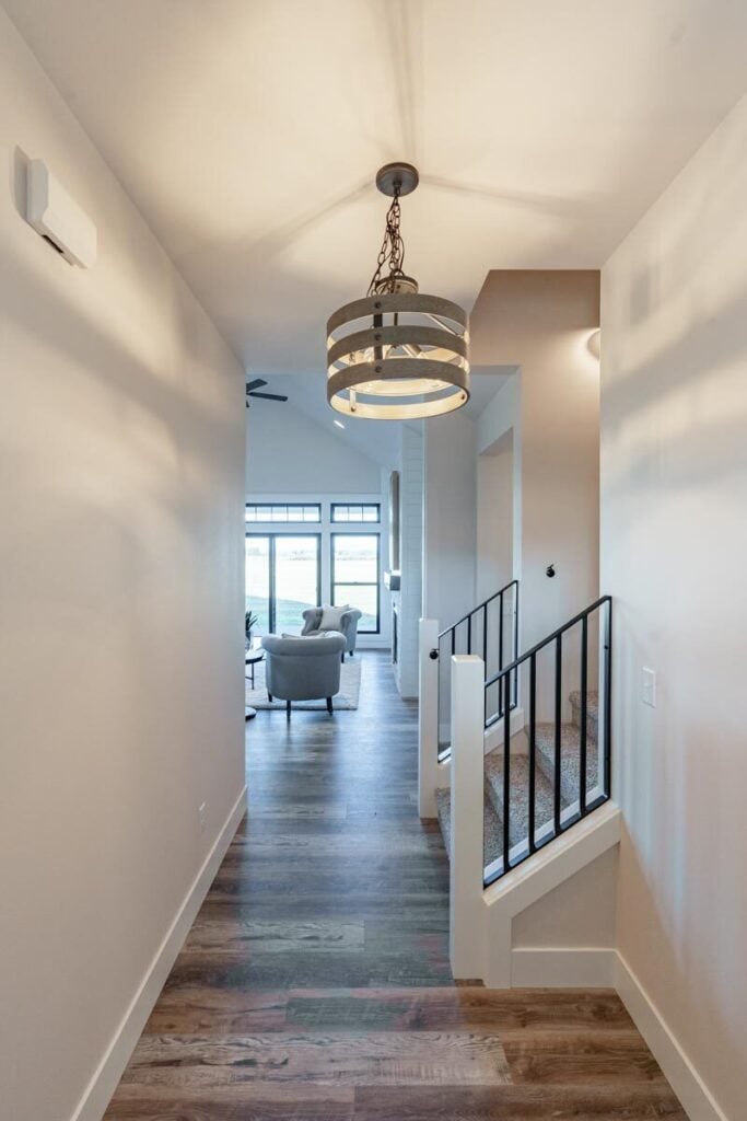 The foyer has a round chandelier and a carpeted staircase leading to the bedrooms.