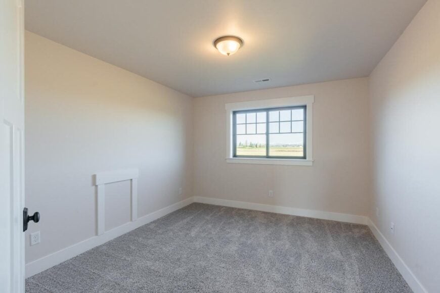Bedroom with beige walls and a framed window that allows natural light in.