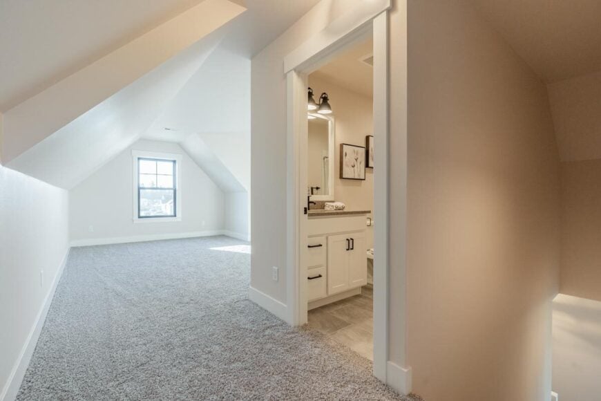 Bonus room with vaulted ceiling, beige walls, and a framed window.