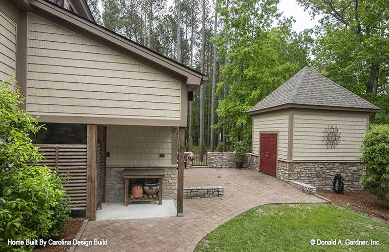 Side exterior view showing the cedar shake siding, stone bases, and an outbuilding.