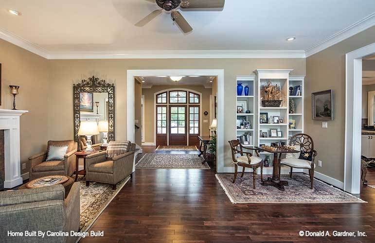 The living room features multiple sitting areas and white built-in shelves.