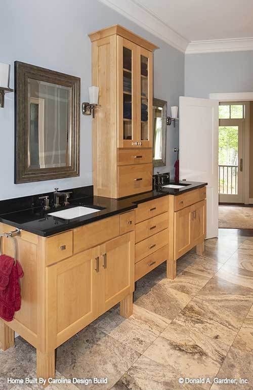 The primary bathroom features his and her vanities separated by a wooden cabinet.