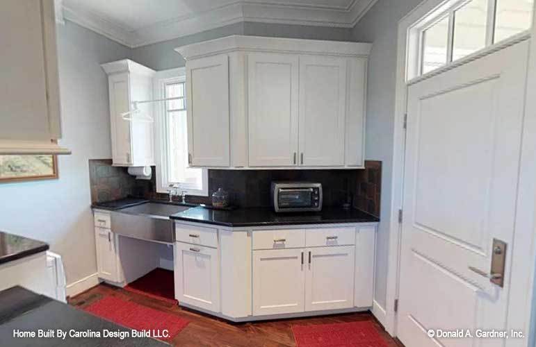 The laundry room is equipped with quartz countertops, white cabinets, and a utility sink.