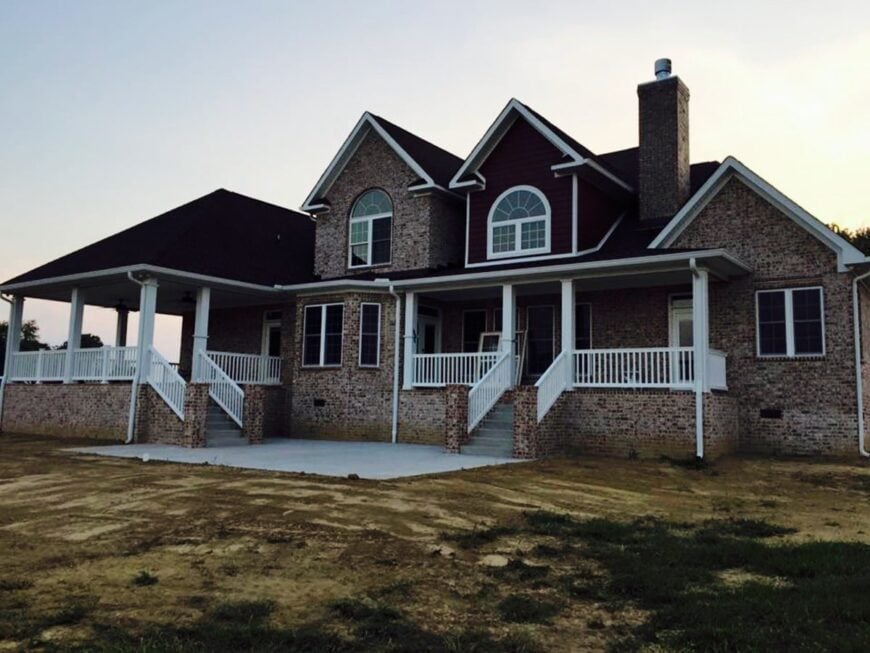 Rear exterior view with covered porches bordered by white railings and columns.