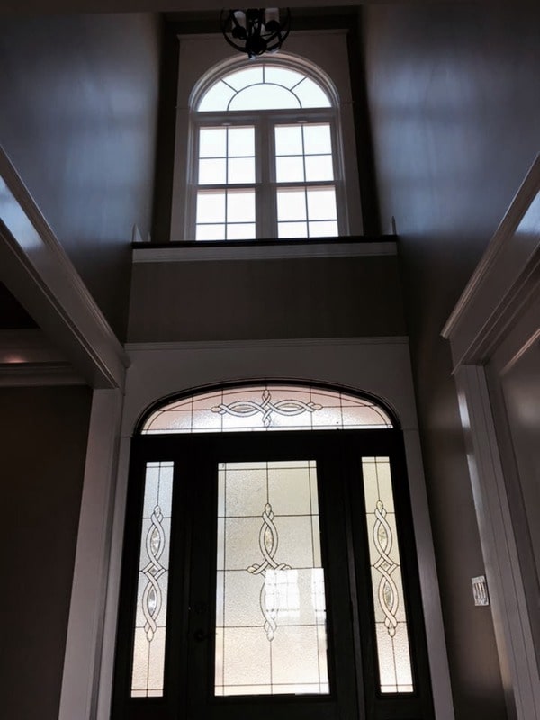 The foyer has a tall ceiling and an arched clerestory window.